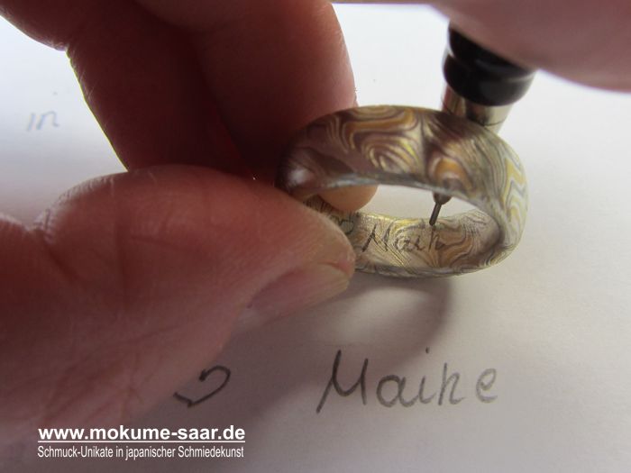 In einen Mokume Gane Ring wird ein Name mit Bleistift eingezeichnet